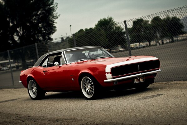 Chevrolet Camaro rouge sur fond de grille