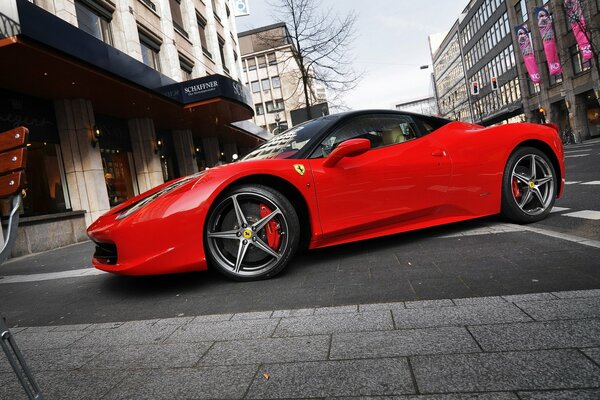 Automobile rossa della ferrari 458 italia sulla via della città