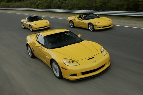 Tres coupés Chevrolet amarillo corriendo por la autopista