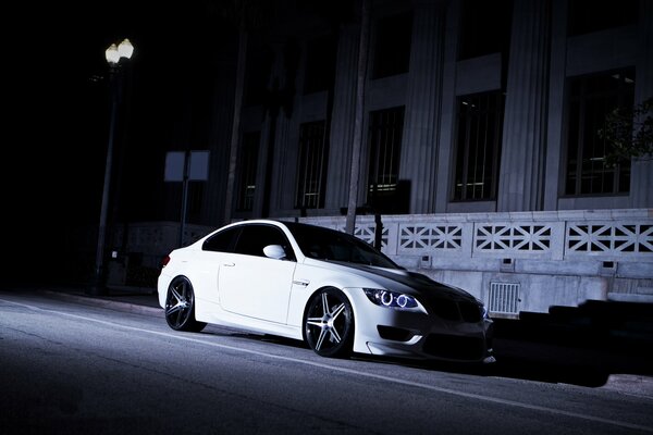 Blanco BMW en la luz de las luces de calle por la noche