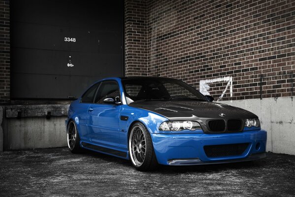 Bmw blue with a carbon black hood on a brick wall background