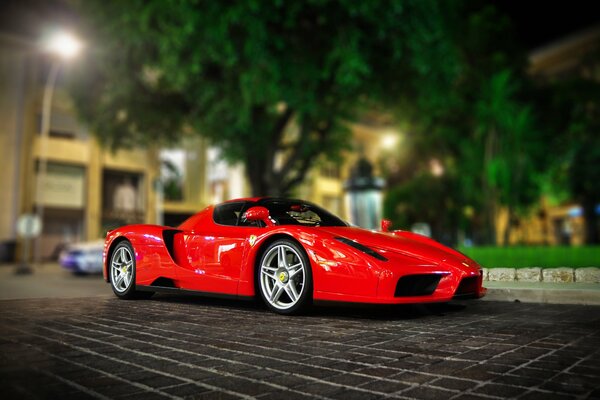Bright red Ferrari in the parking lot against the background of the night city