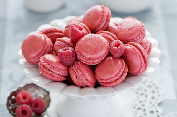 A plate of pink macaroons with raspberries