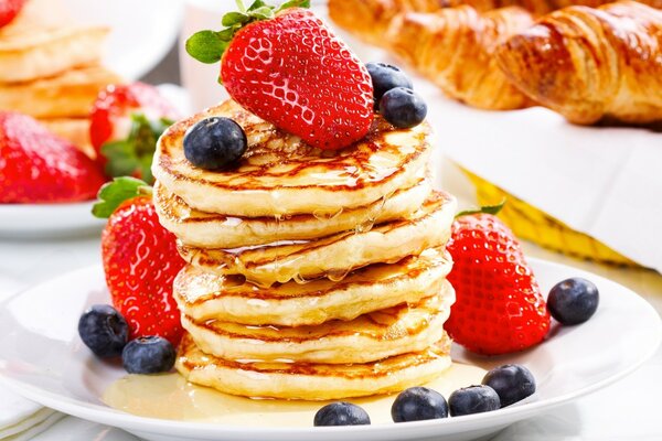 Morning pancakes and croissants with honey and berries