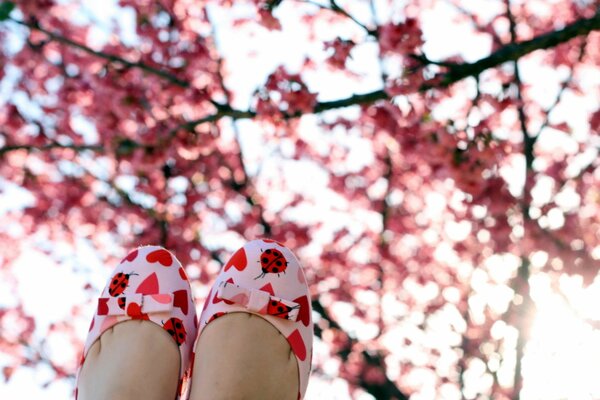 Pies de niña en zapatos en el fondo del Jardín