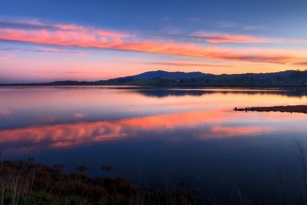 Blauer See, der bei Sonnenuntergang mit dem Himmel verschmilzt