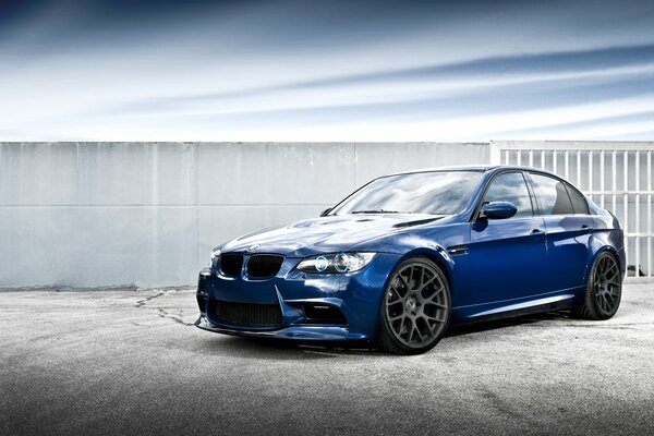 Blue BMW on black wheels and gray background