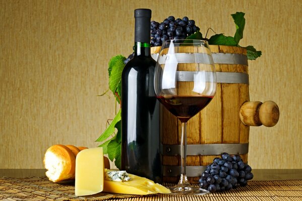 A glass of wine on the background of a barrel of wine and bunches of grapes