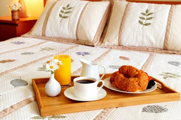 Bandeja con café y croissants y pasteles en la cama