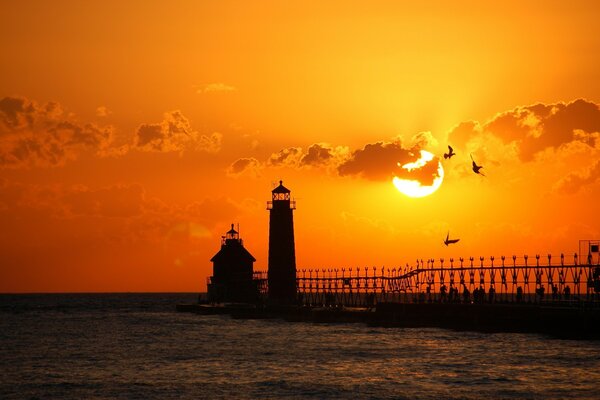 Lighthouse on the background of red-orange sky