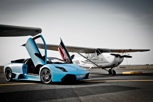 An empty Lamborghini with the doors raised next to the plane