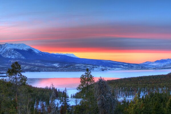 Lago invernale con montagne al tramonto