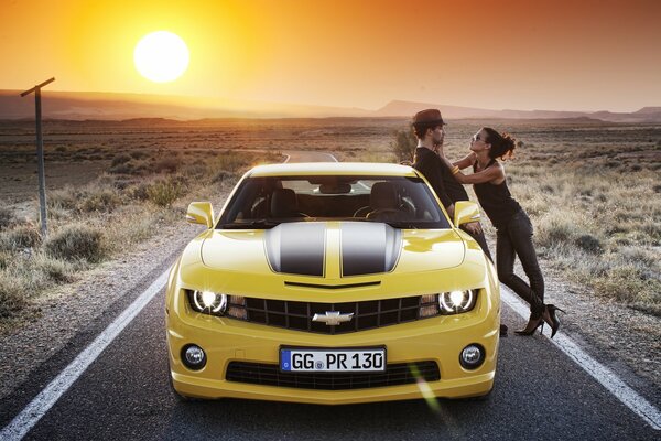 A couple of lovers in a Chevrolet Camaro yellow