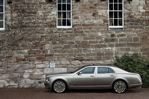 Bentley argent sur fond de mur de pierre de la maison