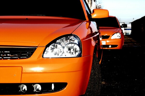 Orange cars in a row on gray asphalt