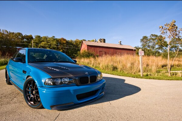 A blue car is driving on a country road