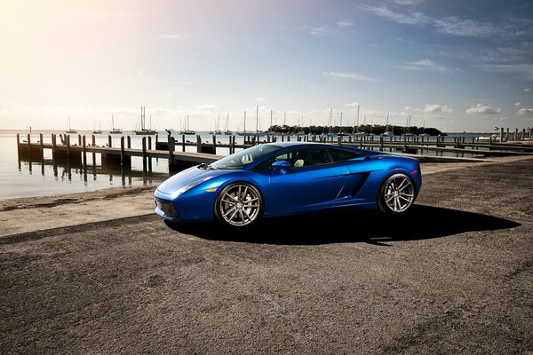 Lamborghini bleu sur le quai à côté du yacht