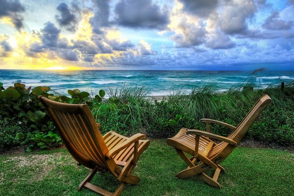 Sunrise, on the background of the sea with two chairs