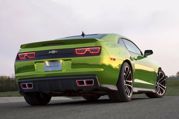 A beautiful, green car is driving along the road