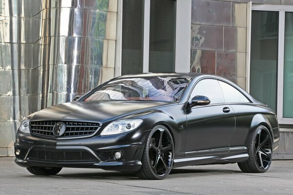 A tuned black Mercedes is parked near the building