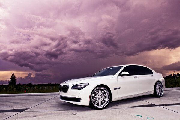 A chic white BMW on a background of purple sky and clouds