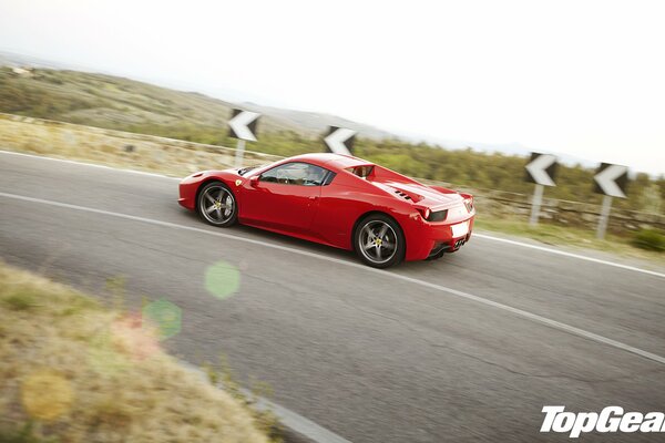 A red sports car rushes along a mountain road