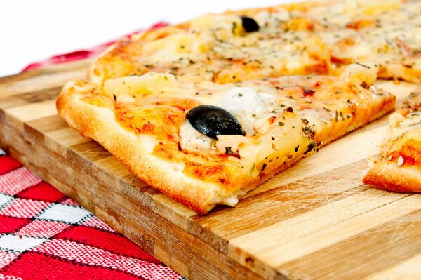 A slice of pizza on a wooden board. Delicious pizza