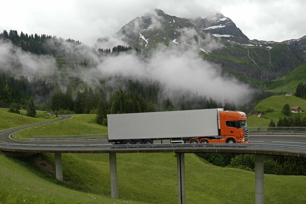 Tracteur orange sur le pont entre les collines vertes