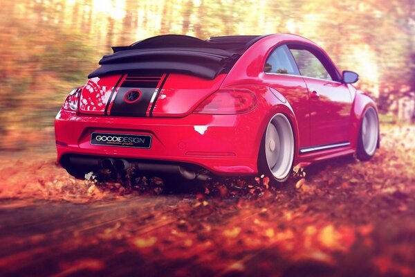 Красный спортивный автомобиль мчится по дороге засыпанной осенними желтыми листьями