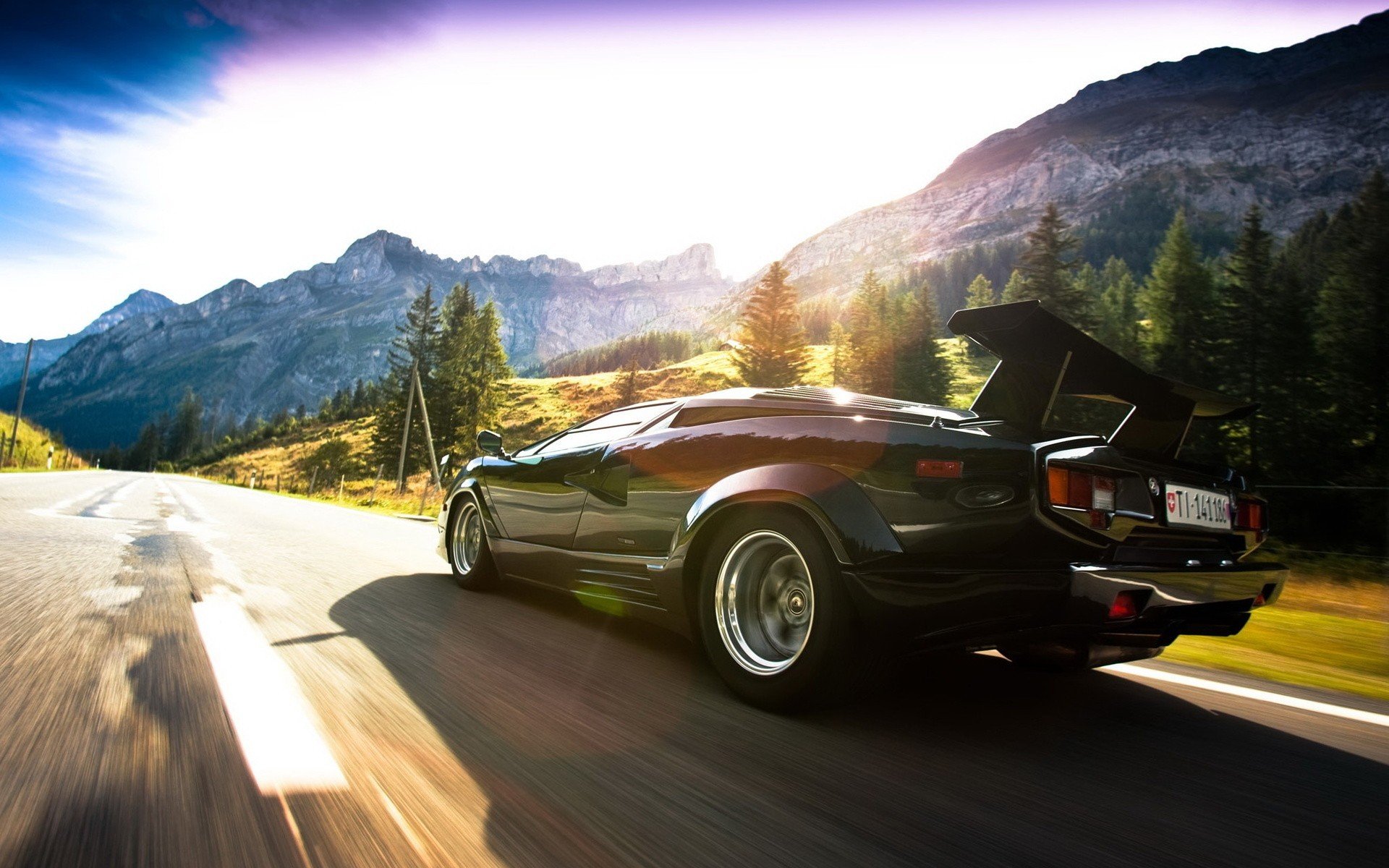 lamborghini lamborghini countach velocità luce sole nuvole cielo aswalt strada montagne rocce bagliore alberi