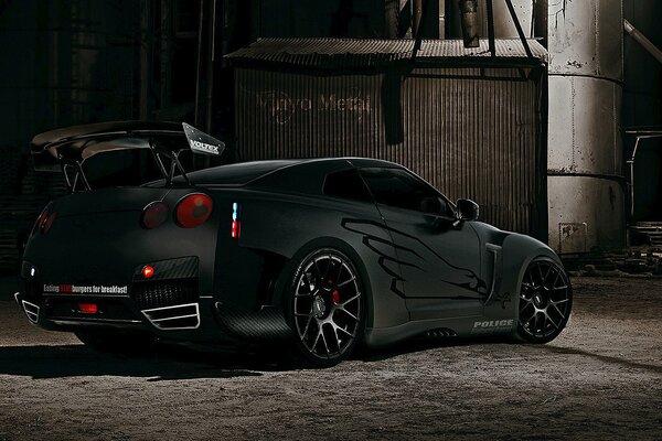 Stylish sports car with a spoiler and beautiful disks on the background of a gray building