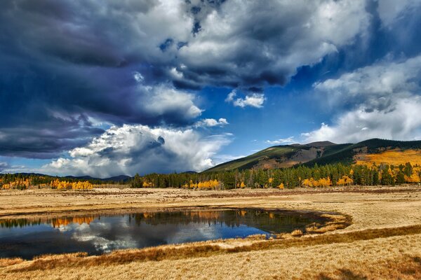 Lago con bosque, montañas y nubes