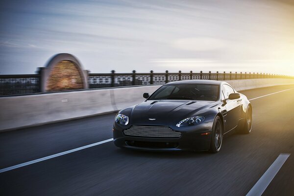 Чёрный Aston Martin едет на скорости по шоссе