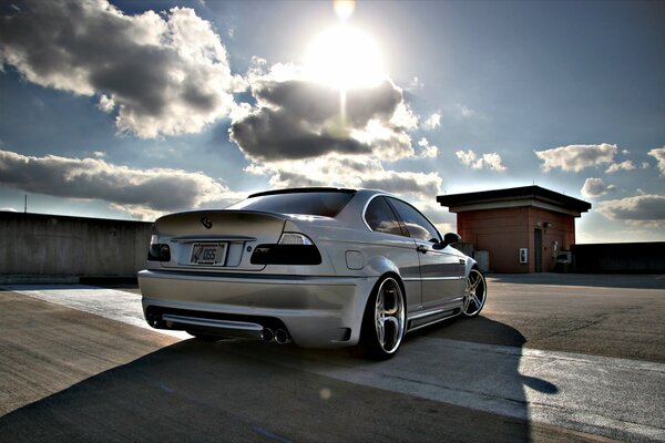 A car in the parking lot and the sun in the clouds