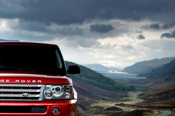 Car red land rover on the background of clouds