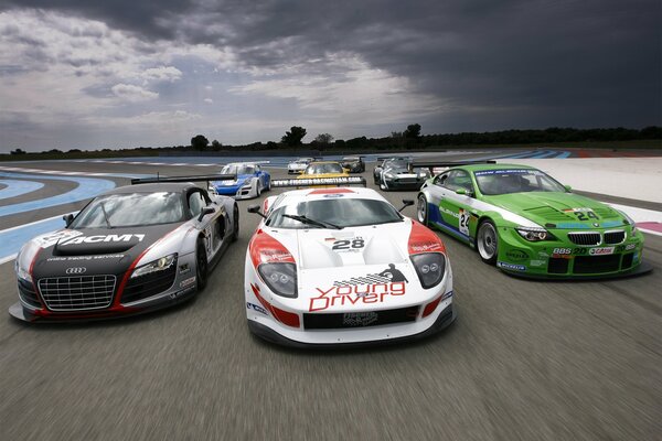 Cool racing supercars at the start of the track against the background of the horizon and gray, overcast sky