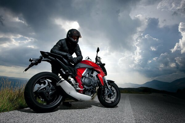 The rider is resting on the road next to his motorcycle