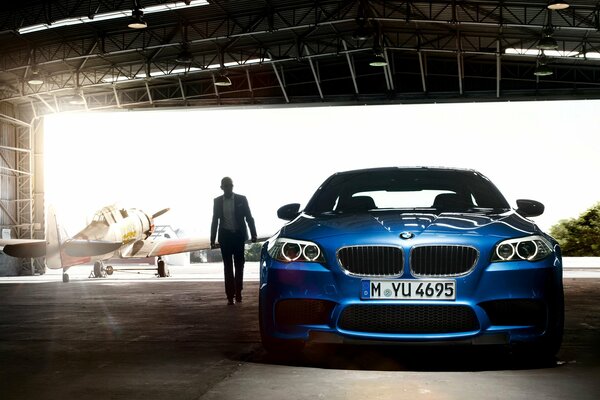 Niebieskie bmw M5 stoi w hangarze samolotu