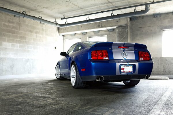Auto niebieski Mustang na tle ściany z cegły