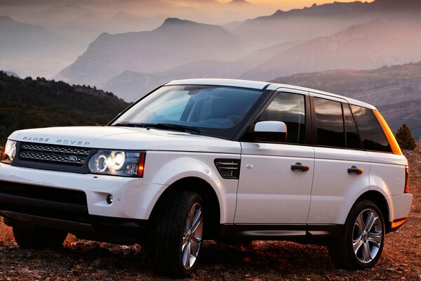 Elegante Jeep range rover blanco al atardecer en las montañas