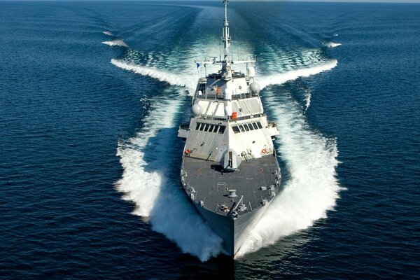 A huge warship in the sea cuts through the waves at great speed