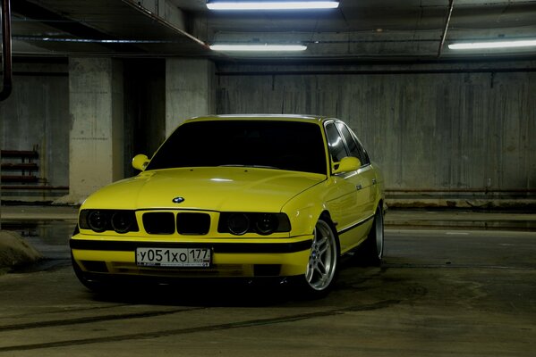 Yellow bmw e34 in an underground parking lot