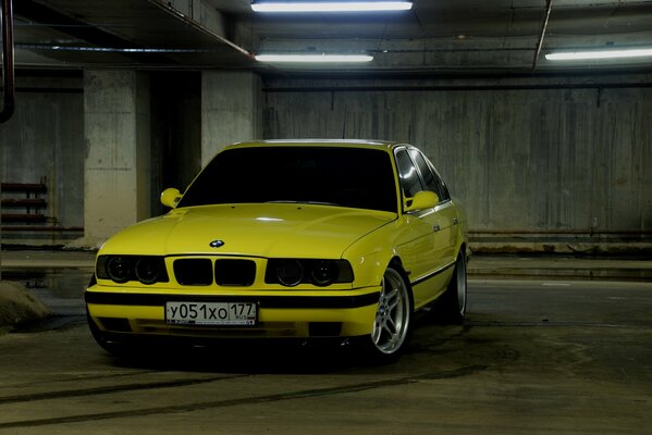 Żółte bmw e34 na parkingu podziemnym