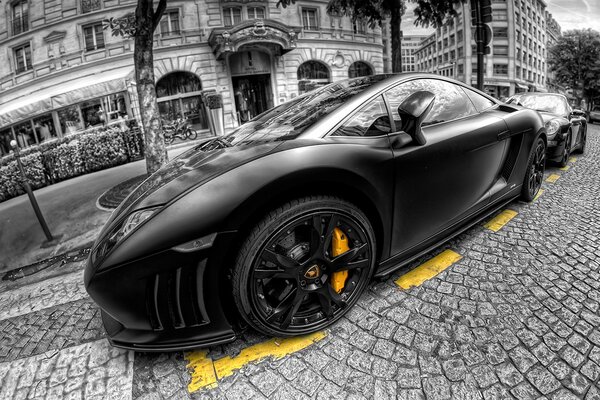 A black beautiful car is parked on the sidewalk