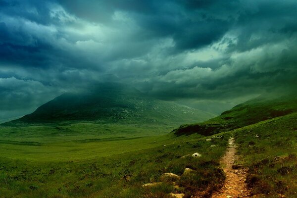 Wanderweg vor dem Hintergrund der Berge, umgeben von Wolken