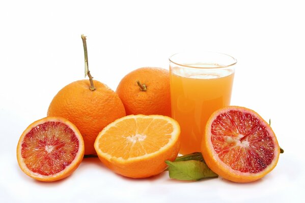 Pomarańcze i grejpfruty obok szklanki soku pomarańczowego