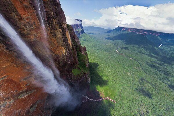 Hoher Wasserfall mit Bergen, Grün und Wolken