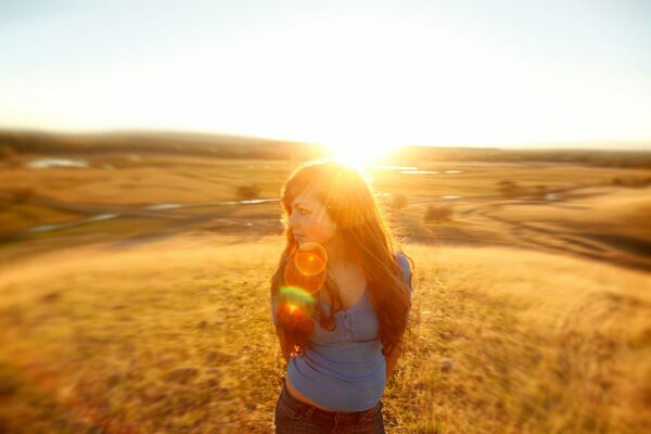 A girl against the background of the sun in a field