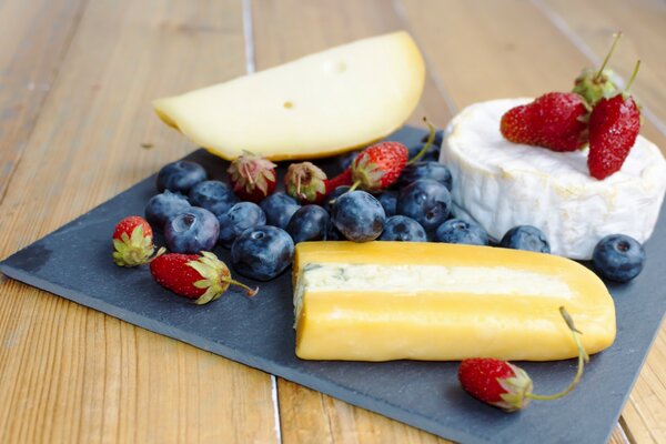 Cheese next to blueberries and strawberries on a napkin