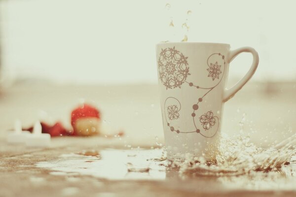 Hohe weiße Tasse mit Mustern. Wasserspritzer